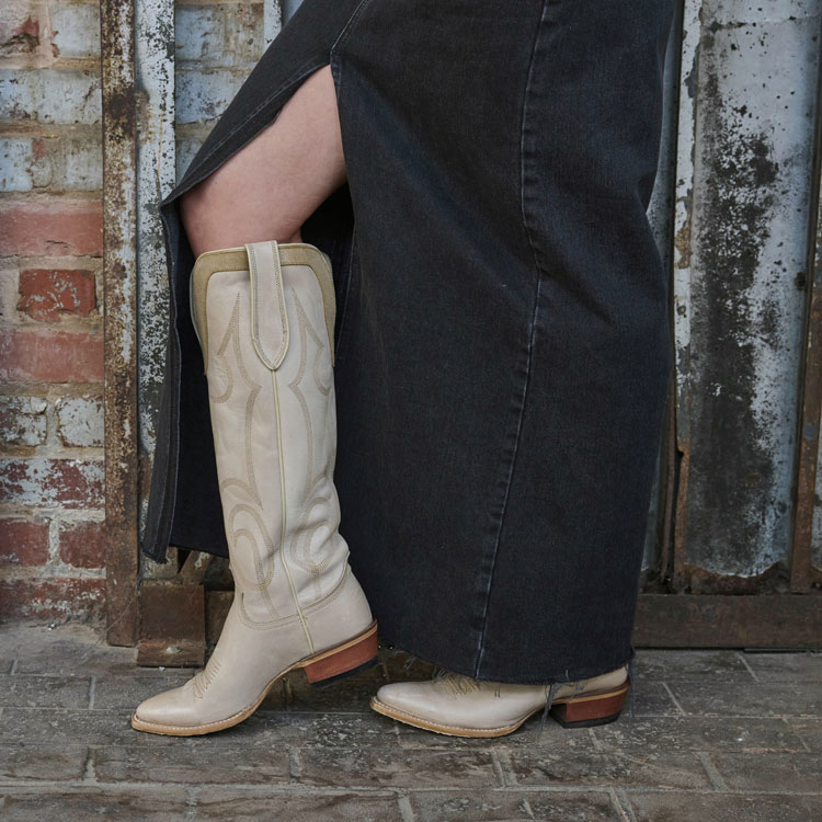 Woman wearing Verlie 17” Western boots in cream with a long skirt. 